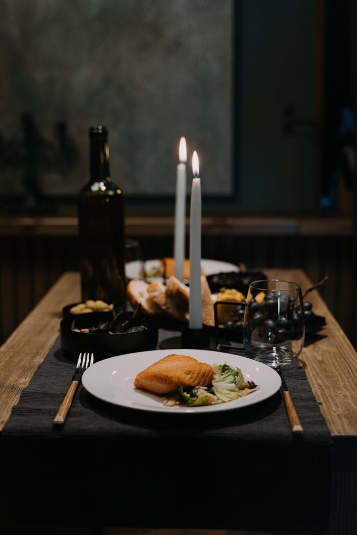 A romantic candlelit dinner setup featuring wine and gourmet dishes in an elegant restaurant.